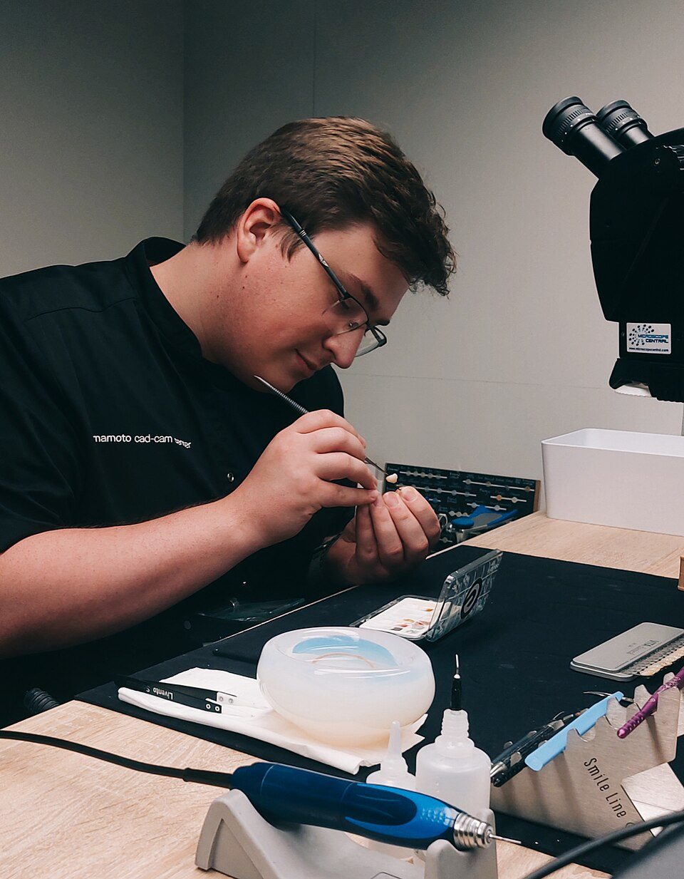 Técnico dental caracterizando peça cerâmica ou zircônia em bancada
